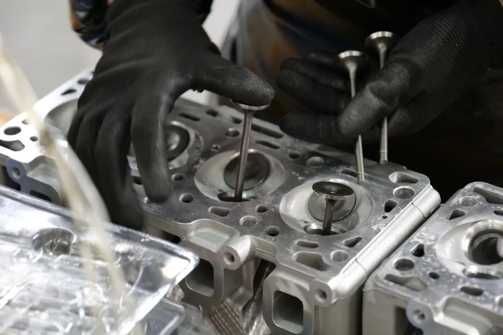 Mani del tecnico che inseriscono le valvole nella testata