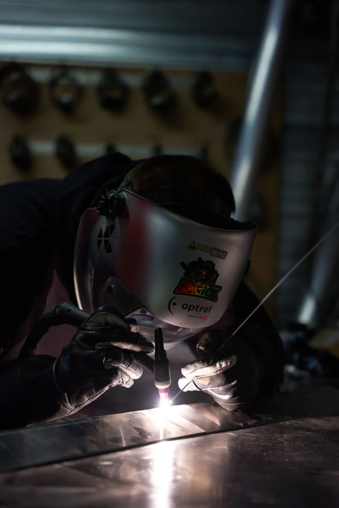 Saldatura TIG su lamiera in officina con maschera di protezione